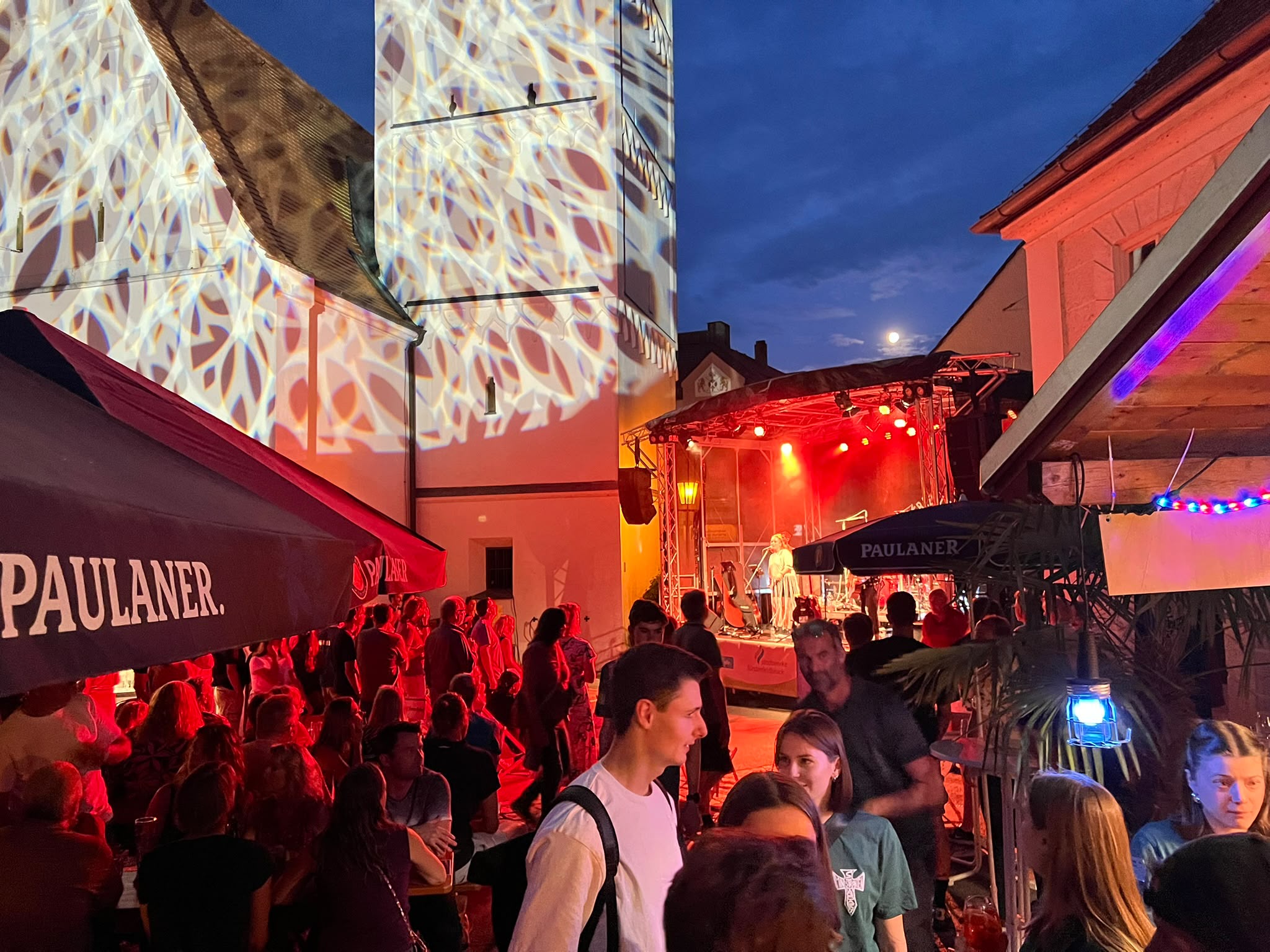 Nächtliche Bühnenshow beim Altstadtfest Fürstenfeldbruck mit rotem Bühnenlicht, Traversen-Rig und Gobo-Projektion auf der Fassade