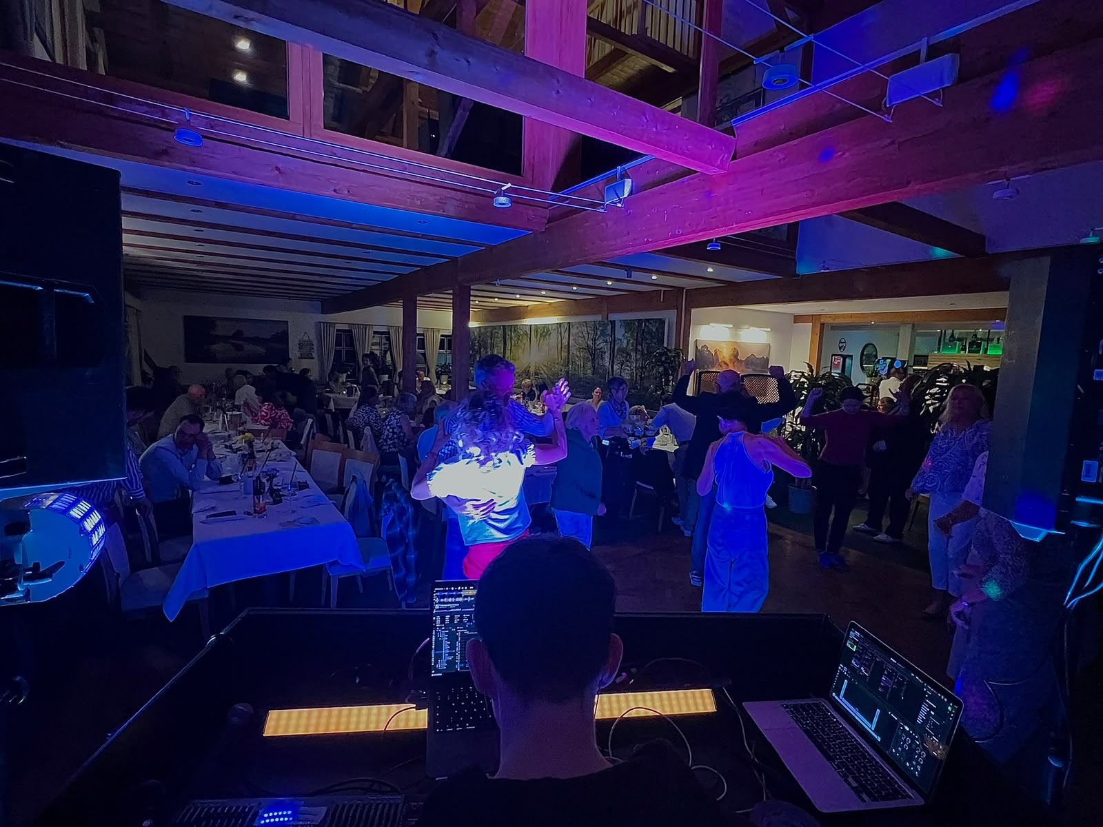 Blick vom DJ-Pult mit Laptop auf die tanzende Menge beim Angolfen im Golfclub Olching, blaues Bühnenlicht