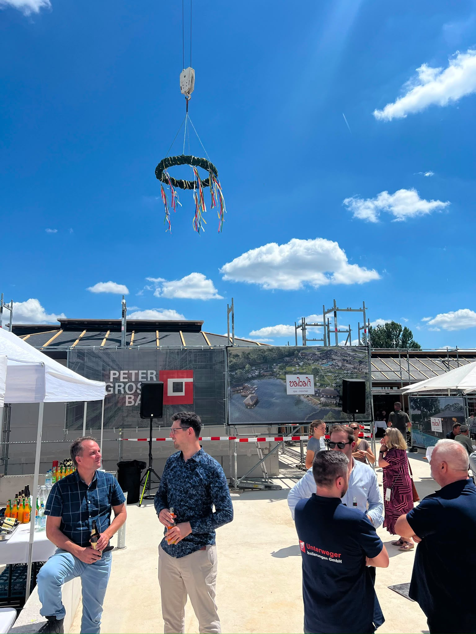 Richtkranz am Baukran vor der Baustelle des Vabali Spa München, im Vordergrund Gäste und eine KET-PA-Box